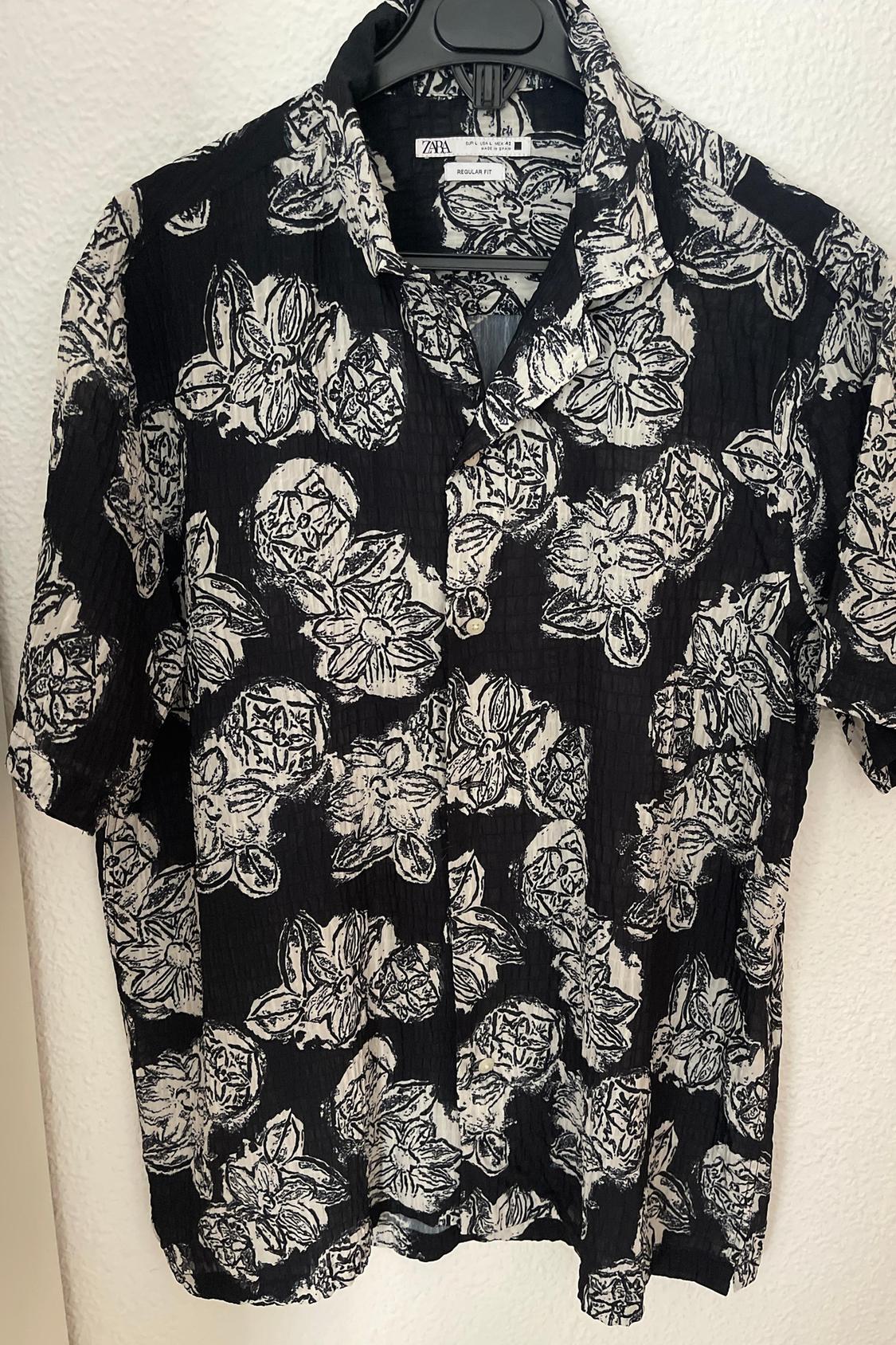 Front view of black shirt with black and white floral print, classic collar and short sleeves.
