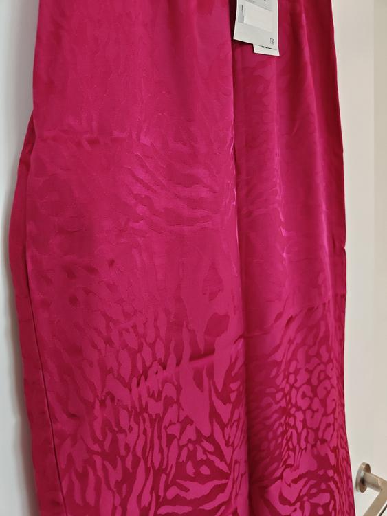 Pink fabric with abstract print hung on a white hanger. Label visible in the top right.