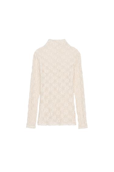 Back view of a beige jumper with lace design and long sleeves.