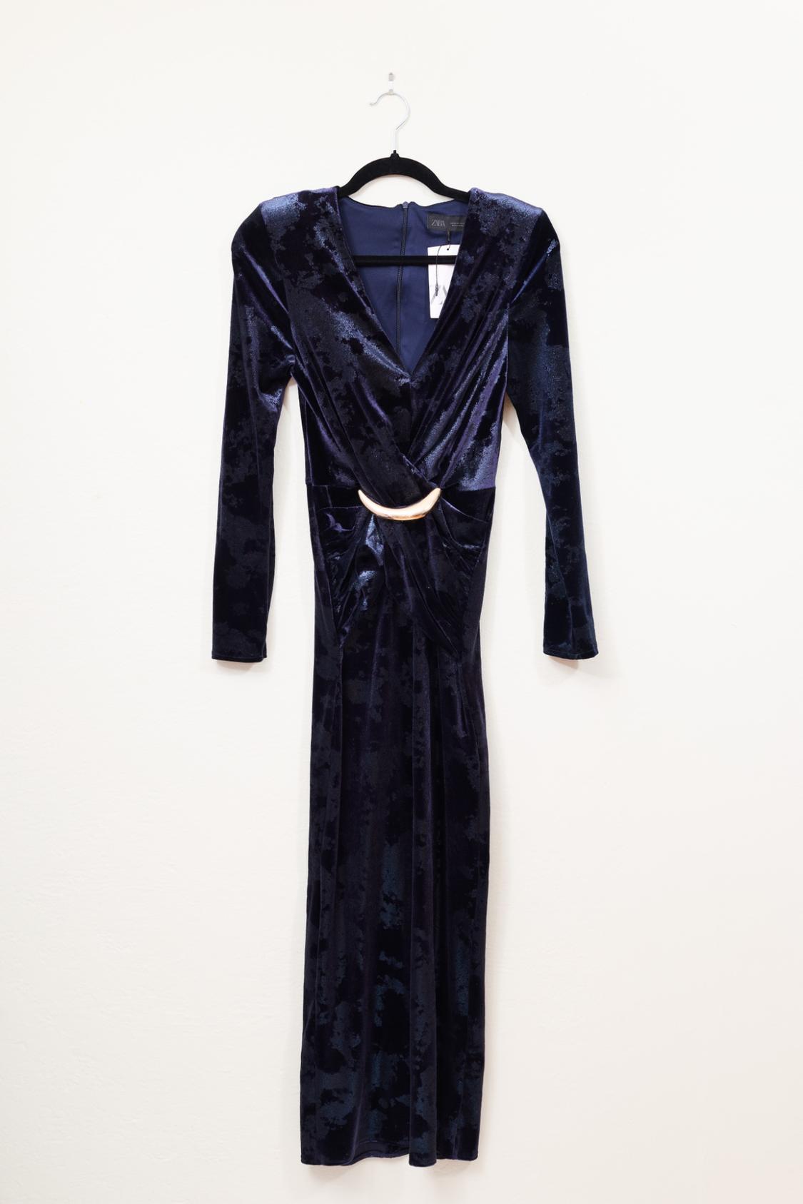 Floor-length navy blue velvet dress with long sleeves, V-neck, golden detailing at the waist, and a Zara label, hung on a black hanger.