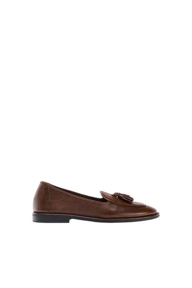 Brown leather tassel loafer, black sole, on a white background. Classic and elegant design.