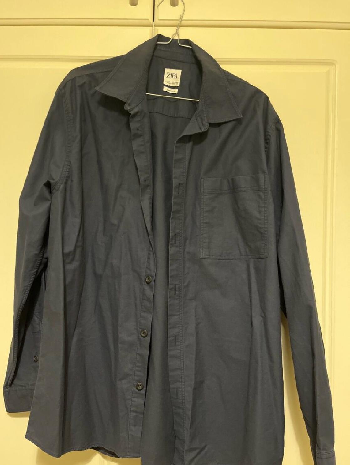 Front view of a blue shirt with a front pocket and buttons.