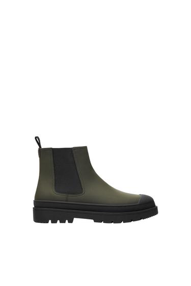 Olive green Chelsea boot with black sole and black elastic side panel, side view on a white background.
