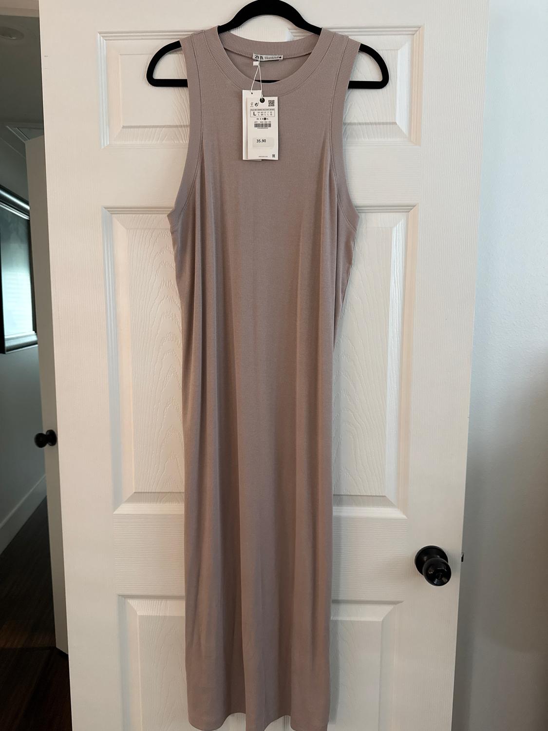 Sleeveless beige dress hanging on a white door. Visible tag with a price of $35.90. Well-lit indoor setting.