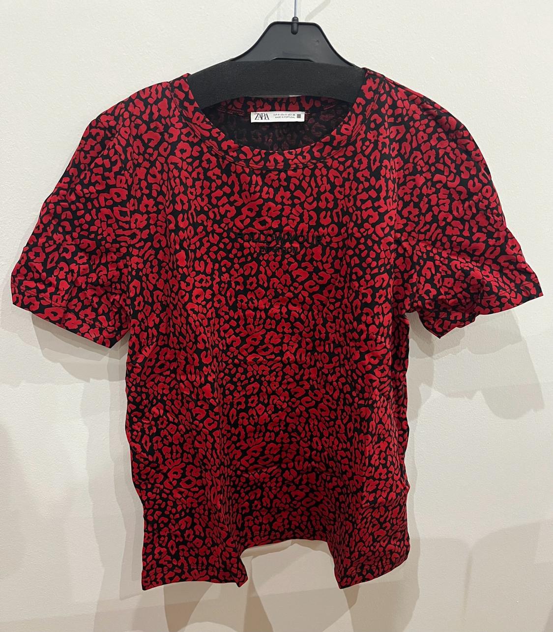 Red and black leopard print short-sleeved casual T-shirt on a hanger. Visible text: ZARA and FOLLOW YOUR INTUITION.