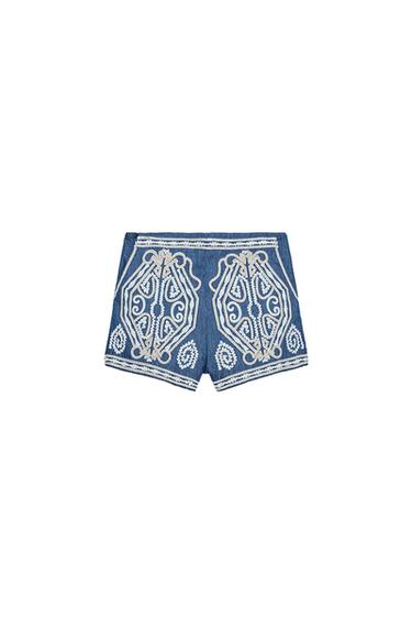 Front view of blue shorts with decorative white embroidery.