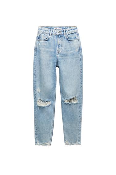 Front view of worn blue jeans with front pockets and rips on the legs.