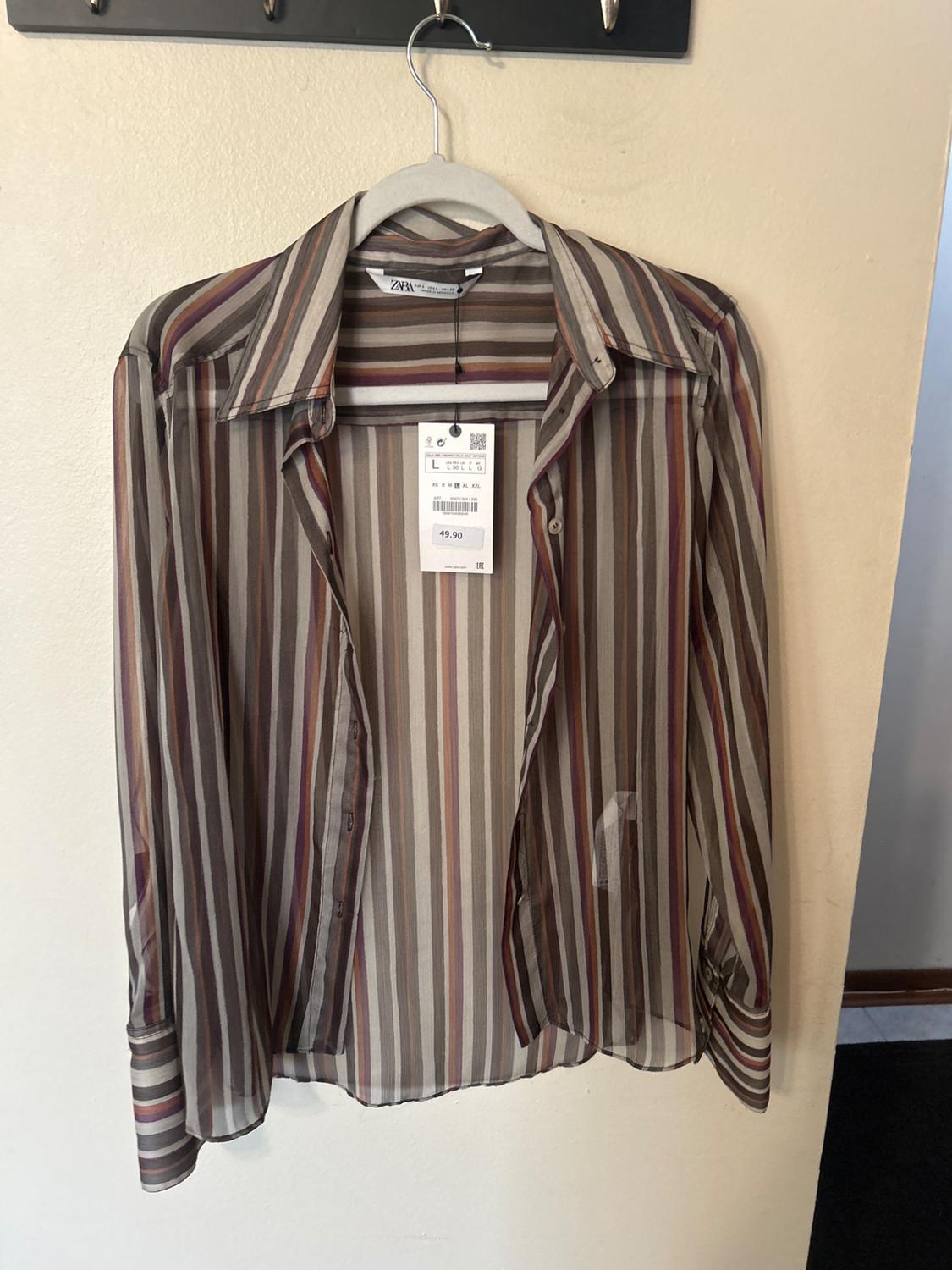 Vertical striped shirt in shades of brown and beige hanging on a hanger, with a price tag of 49.90.