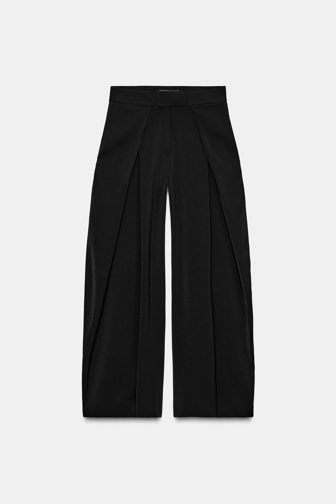 Front view of black wide-leg trousers with front pleats and concealed side pockets. Front zip fastening.