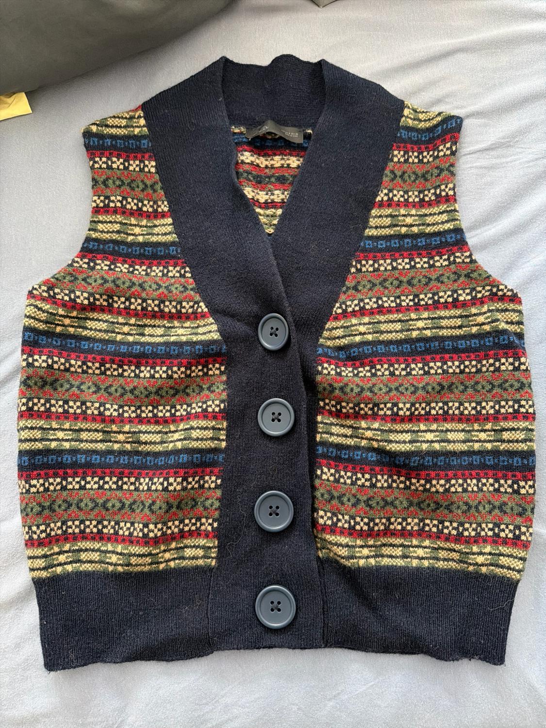 Casual-style knitted waistcoat with a V-neck and buttons. Multicoloured geometric striped print with dark trims, on a light fabric.