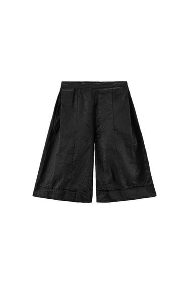Black crinkled fabric shorts with an elasticated waist and a wide cut, on a white background.