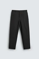 Front view of regular fit black trousers with elasticated waistband, front and back jetted pockets, zip and button fastening.