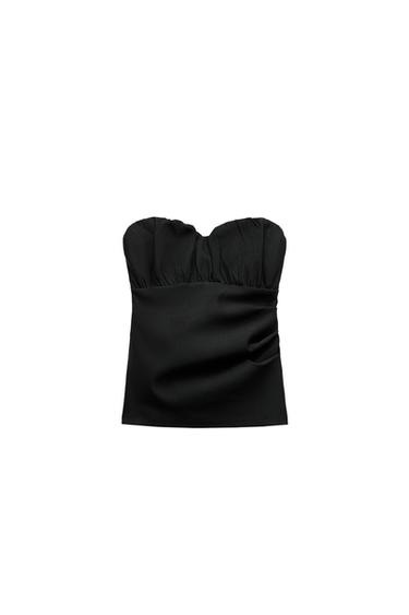 Front view of a black strapless top with ruching at the chest.