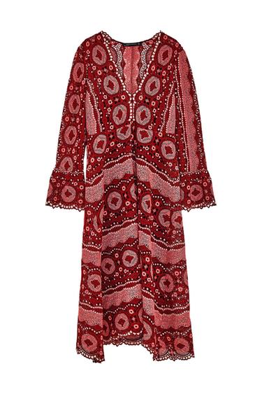 Long-sleeved dress with a V-neck. Design featuring open-work details and circular patterns in shades of red and pink on a white background.