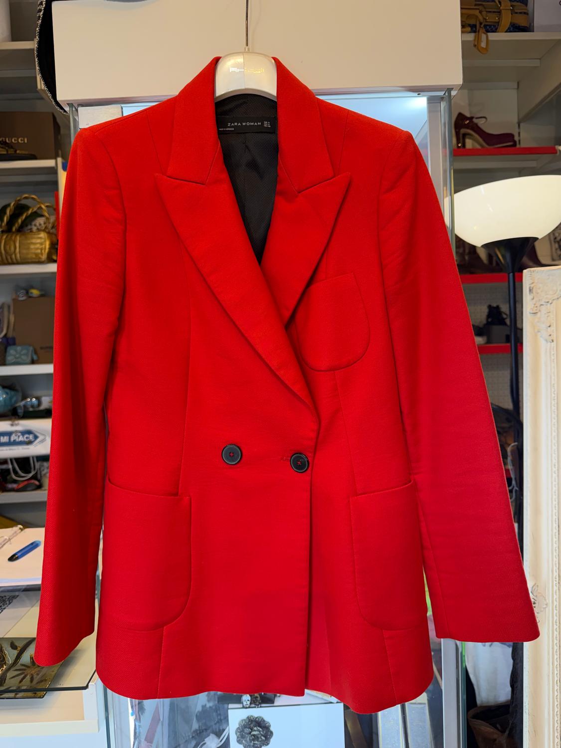 Women's red double-breasted jacket with large pockets, hanging on a hanger in a clothes shop.