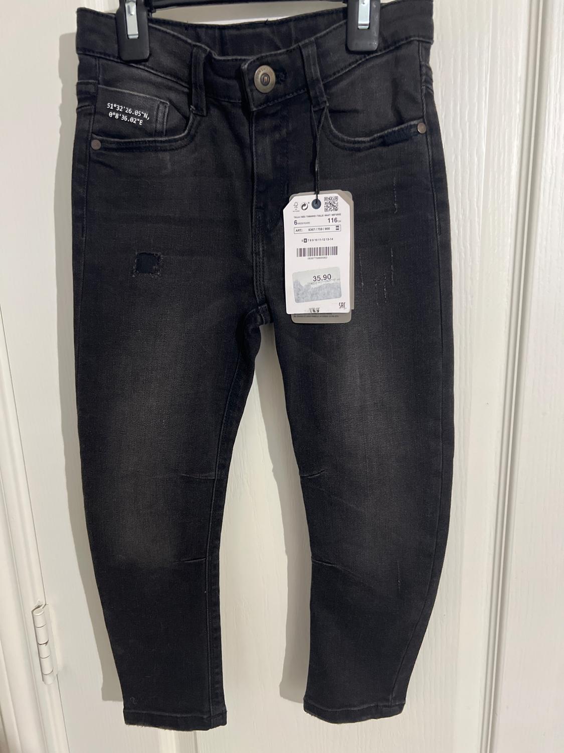 Black pants hanging on a hanger with a price tag of 35.90. Coordinates printed on the small pocket.