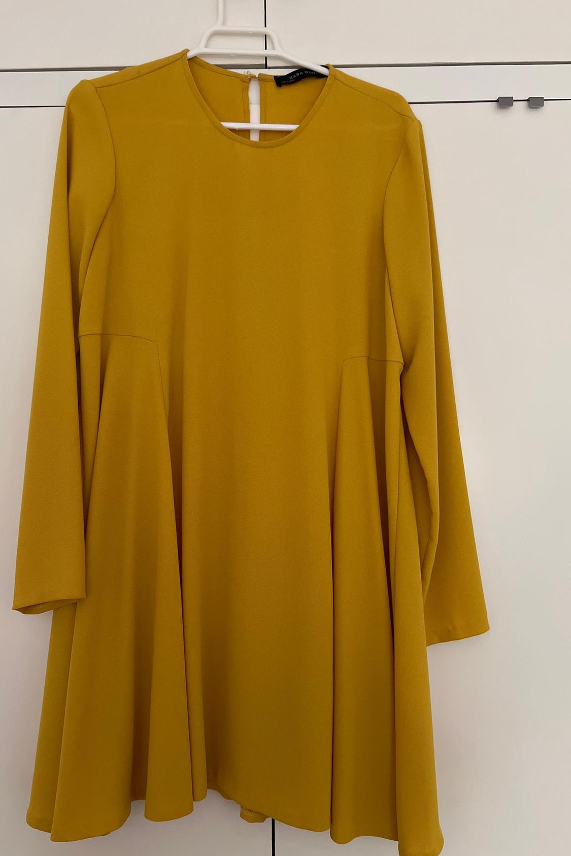 Front view of yellow long-sleeved dress with loose fit.