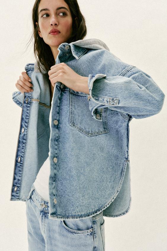 Polodlouh� bunda z modr�ho denimu se sn�matelnou kapuc�, dlouh�m ruk�vem a p�edn�mi kapsami s patkou.