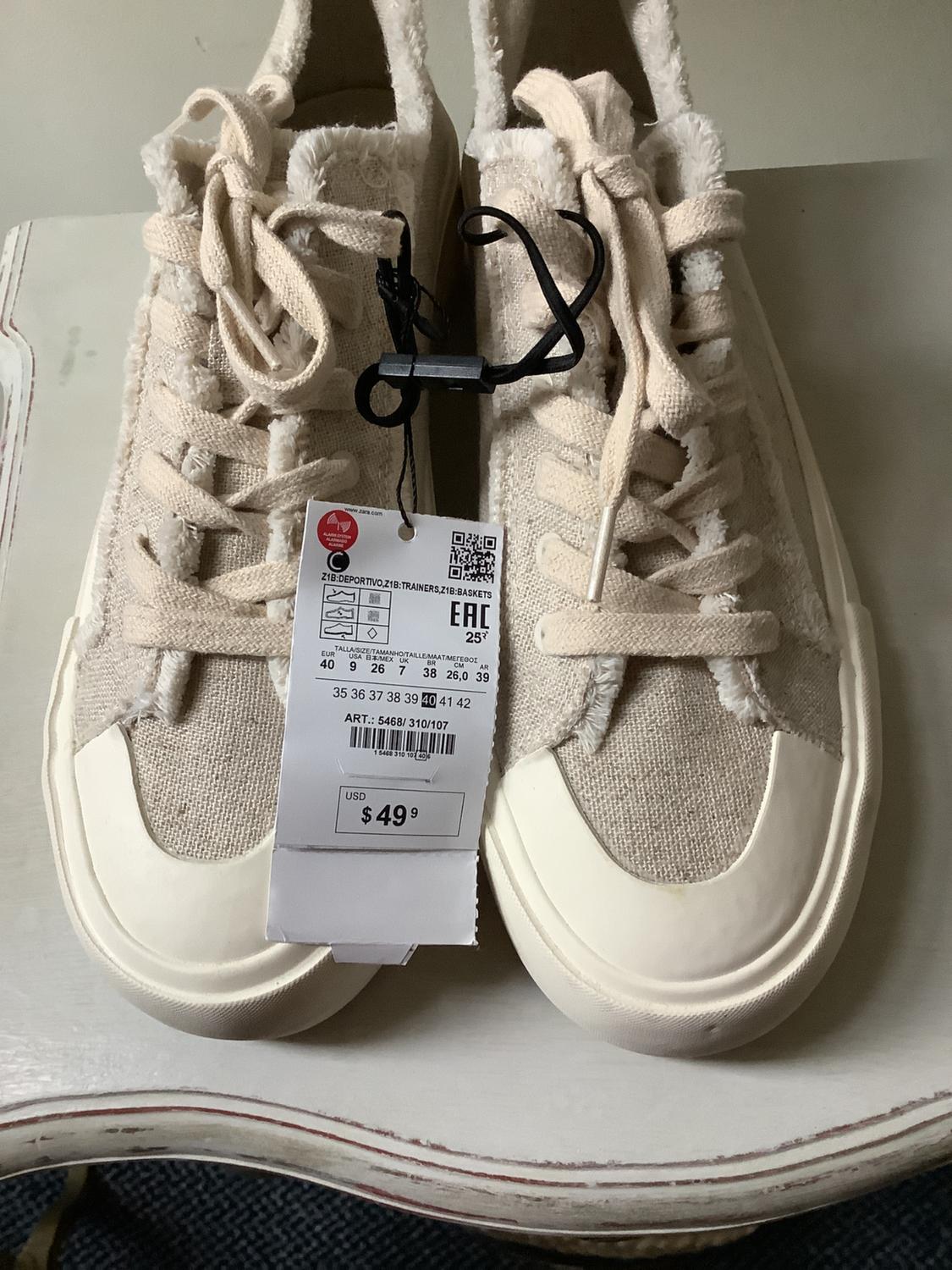 Beige trainers with a white toe cap and frayed edges. Label: Z1B:SPORTSWEAR, Z1B:TRAINERS, Z1B:BASKETS, USD $49.99.