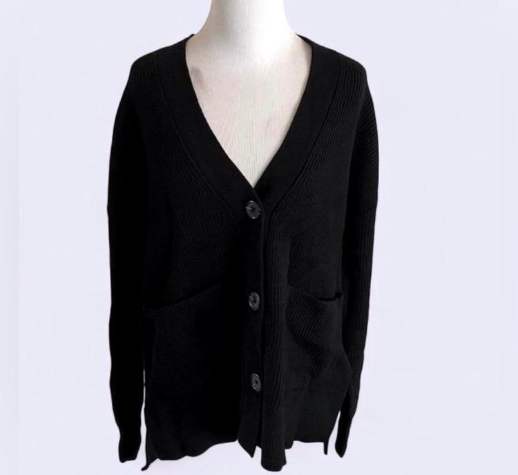 Black knitted cardigan with large buttons and front pockets, displayed on a mannequin against a white background.