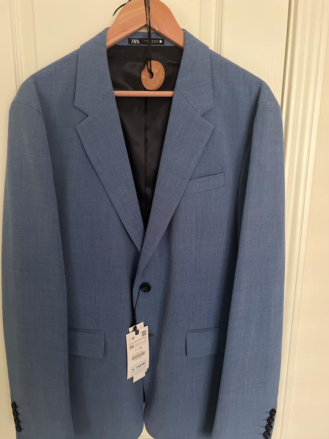 Blue jacket hanging on a wooden hanger, with a visible price tag of 129.00. White background.