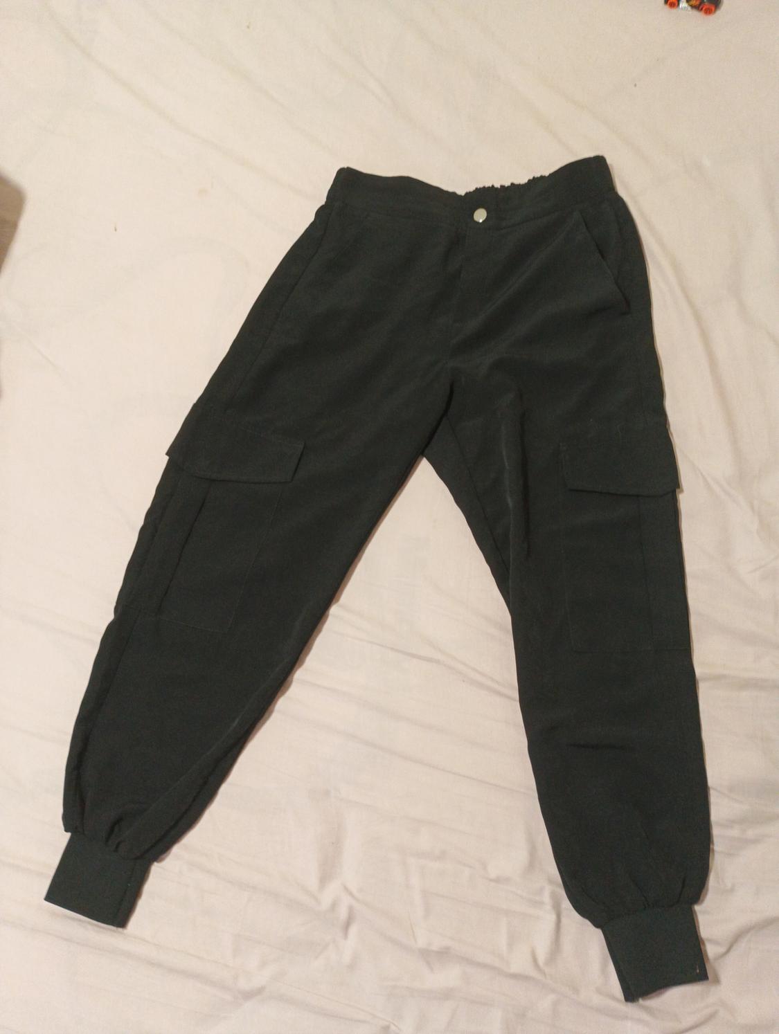 Dark cargo trousers with side pockets and elasticated cuffs, laid flat on a light surface.