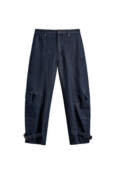 Front view of indigo cargo pants with patch pockets on the legs and adjustable hem with tabs. Concealed front closure.