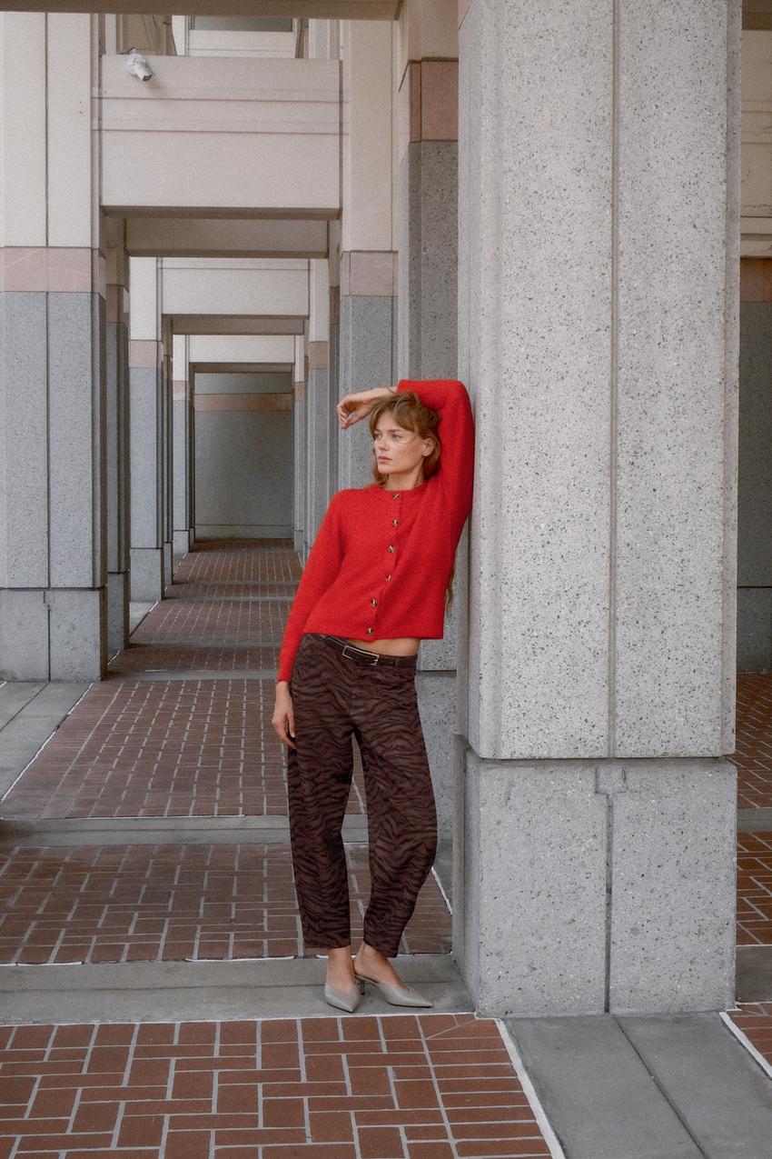 Set aus roter Strickjacke mit Knöpfen und braunen Hosen mit Tiermuster.