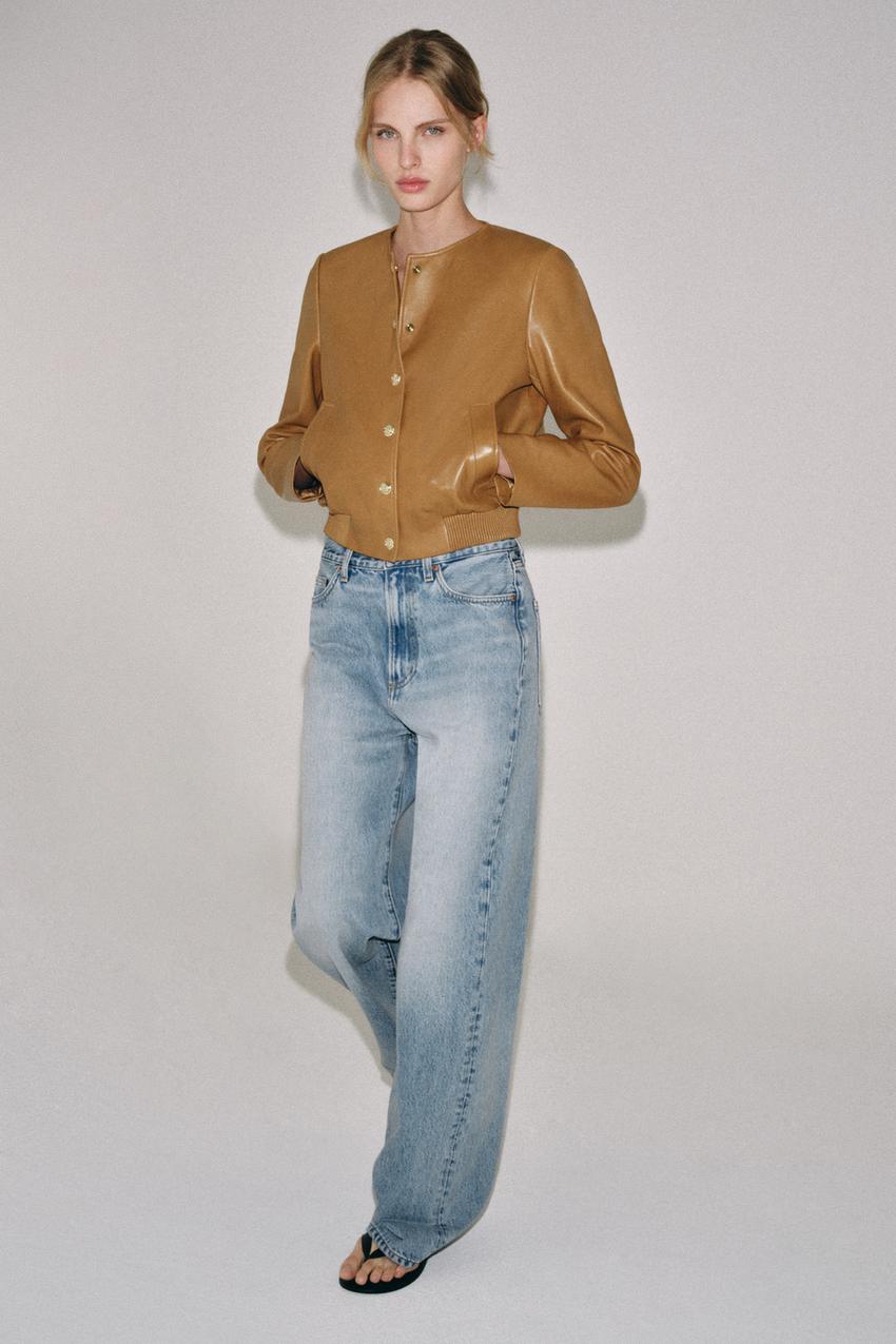 Caramel long-sleeve jacket set with round neck, buttons, and side pockets, blue jeans, and sandals.