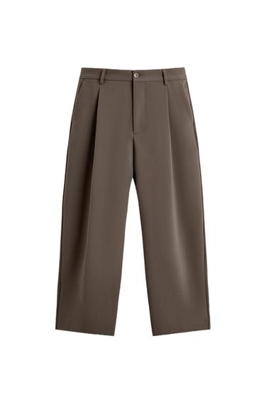Front view of brown pants with pleats, side pockets, and button closure.