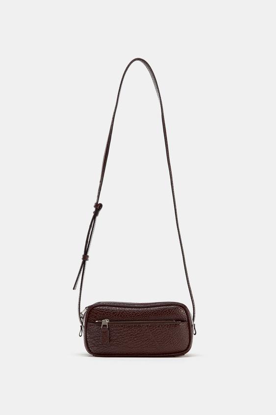 Vorderansicht einer bordeauxroten Mini-Bowlingtasche mit genarbtem Effekt, Rei&szlig;verschluss-Vordertasche und verstellbarem Schultergurt.