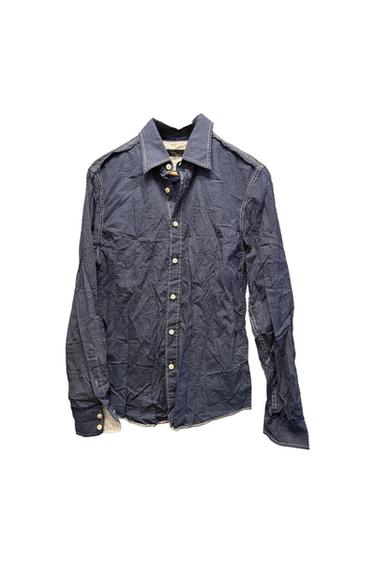 Navy blue long-sleeve shirt with a white polka dot print, crinkled texture, light-colored buttons, and visible stitching on a white background.