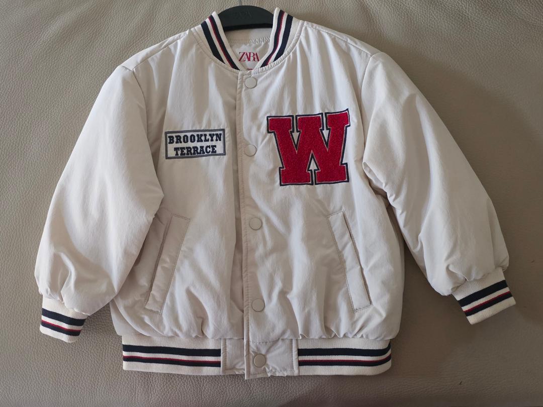White varsity jacket with "BROOKLYN TERRACE" and red "W" patches. Black and red striped details on cuffs and collar.