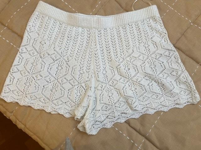 White lace shorts with a geometric design on a beige bedspread.
