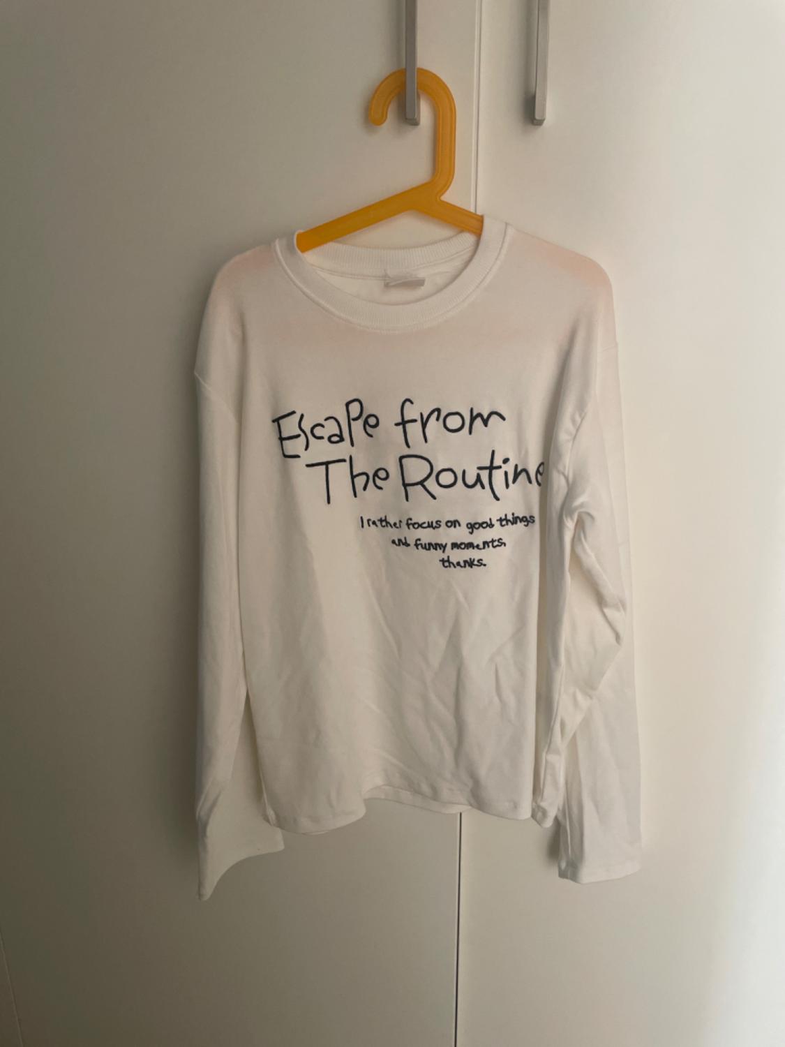 Front view of a white t-shirt with the text 'Escape from The Routine'.