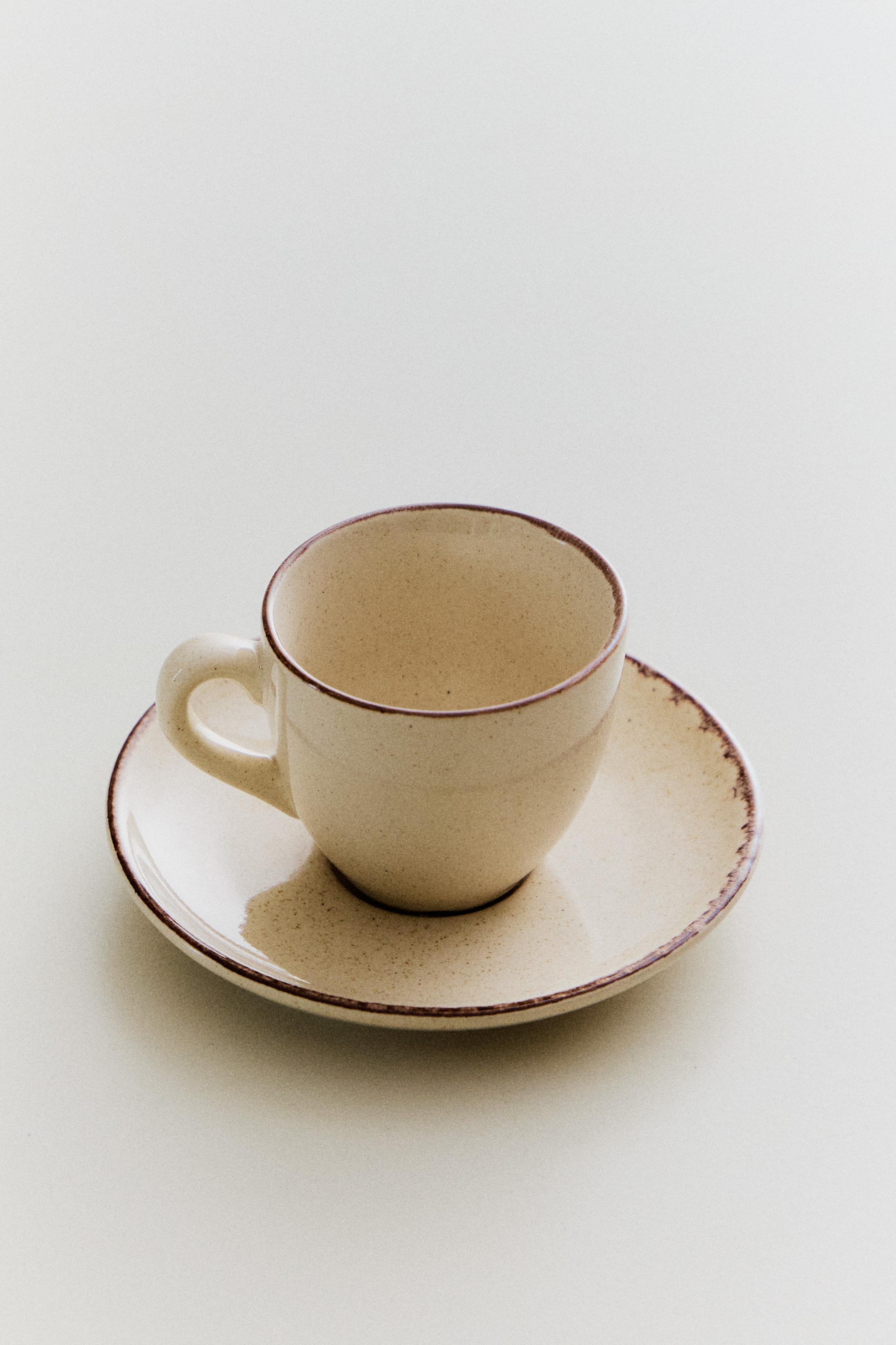 STONEWARE COFFEE CUP AND SAUCER WITH DISTRESSED RIM