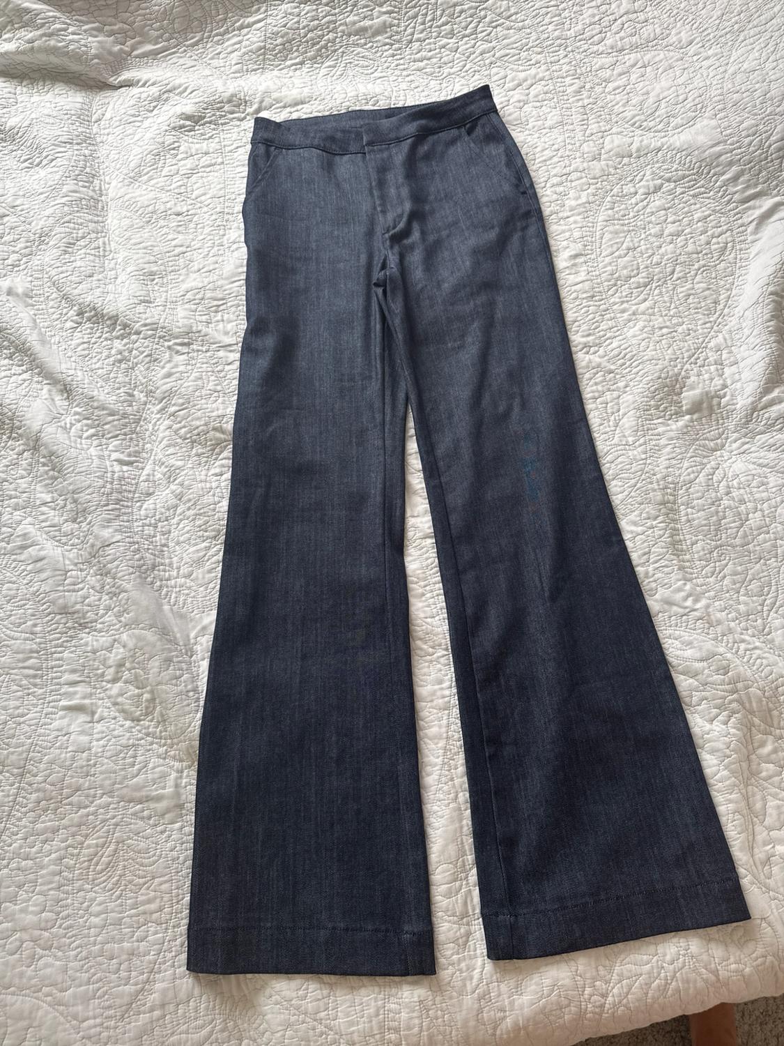 Dark blue wide-leg high-rise jeans, laid out on a white quilted bedspread.