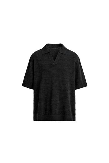Front view of a black knit polo shirt with an irregular texture, lapel collar, front opening, short sleeves, and ribbed trim.