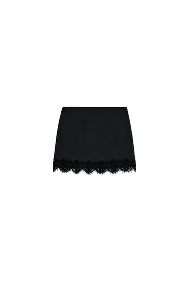 Front view of short black culottes with a lace hem and concealed side fastening.