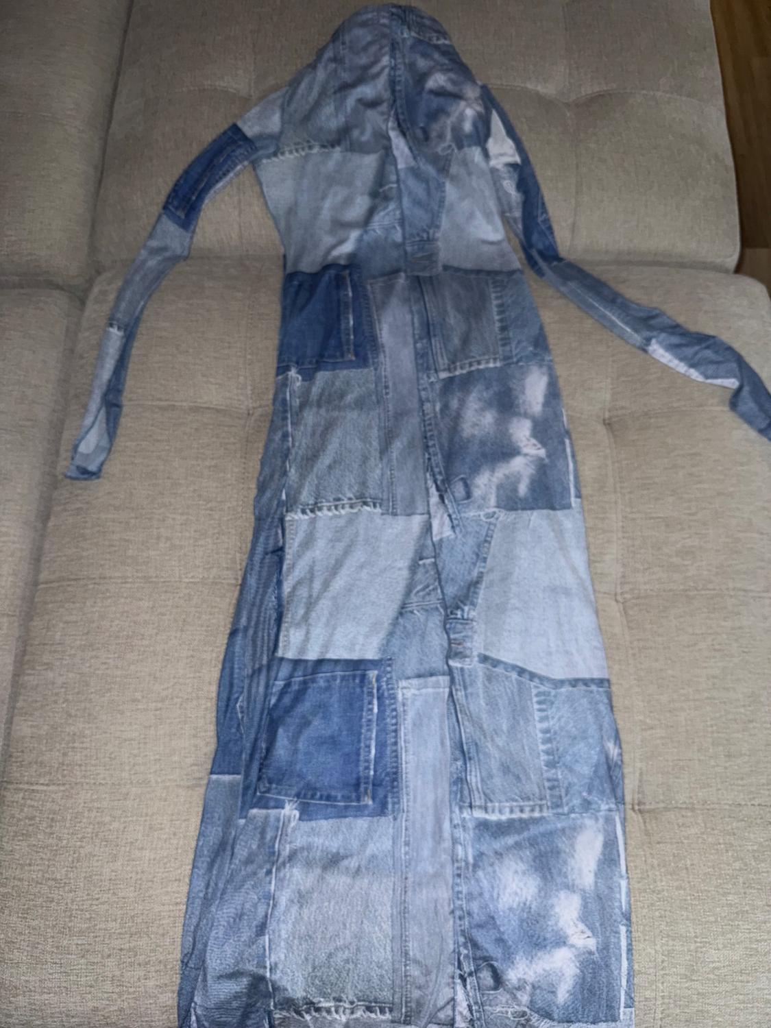 Long denim coat with hood, patchwork design in blue tones, on a beige sofa.