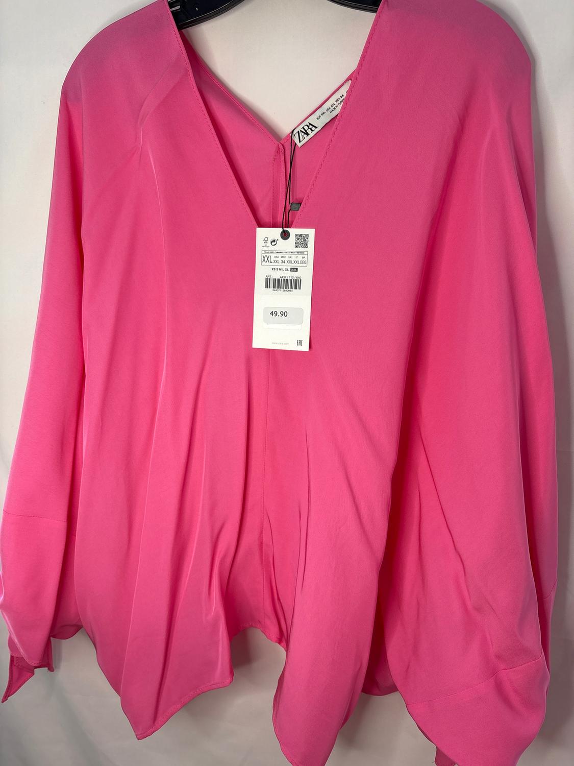 Pink V-neck blouse hanging on a hanger. Visible tag with price of 49.90. White background.