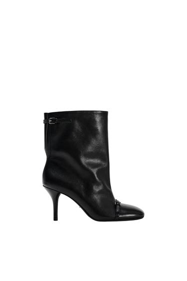 Black high-heeled boot with side buckle on a white background. Elegant and minimalist design.