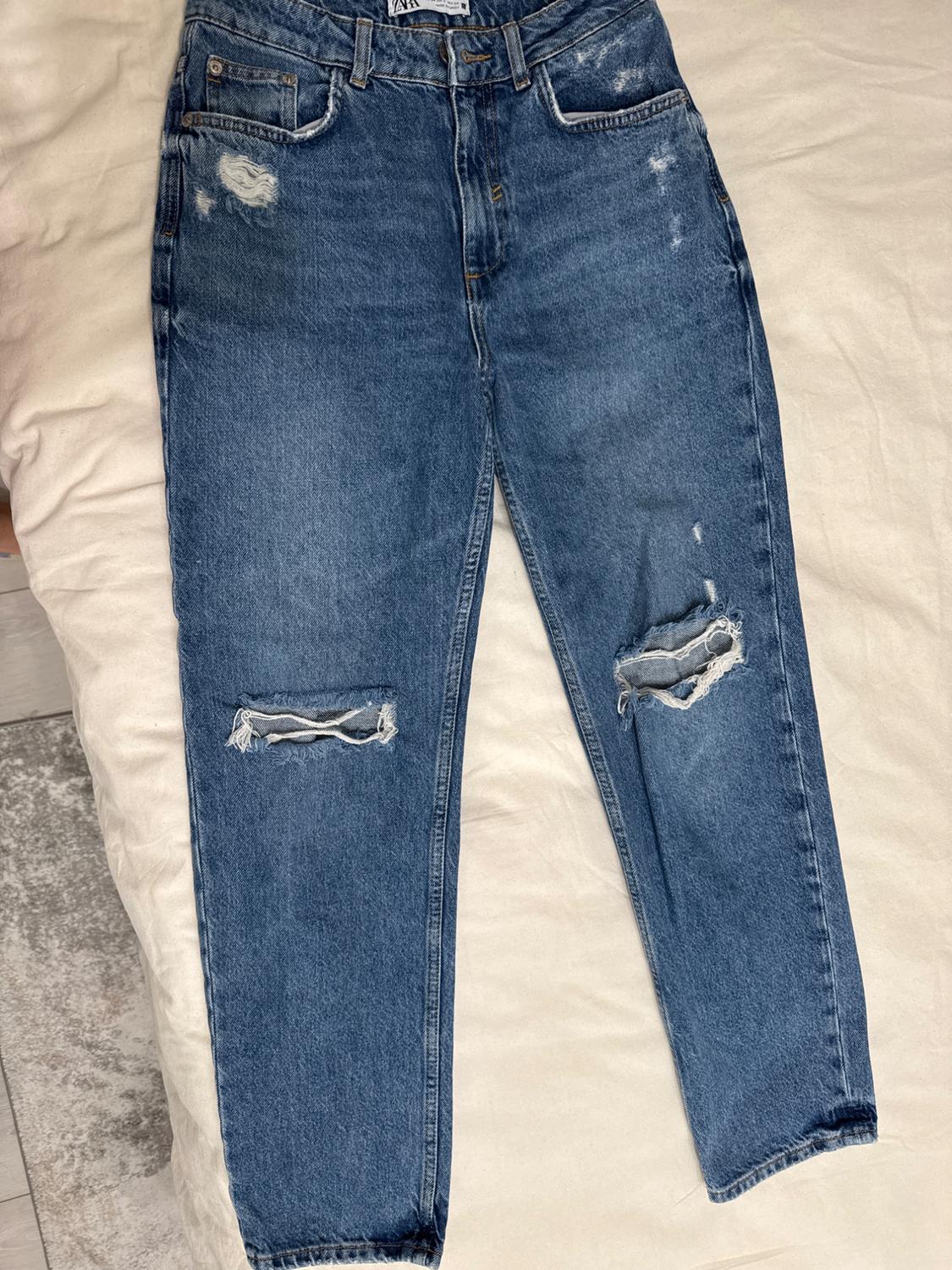 Front view of blue jeans with distressing and front pockets.