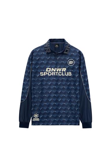 Front view of a blue t-shirt with a geometric pattern and text 'DNWR SPORTCLUB', 'move persist'.