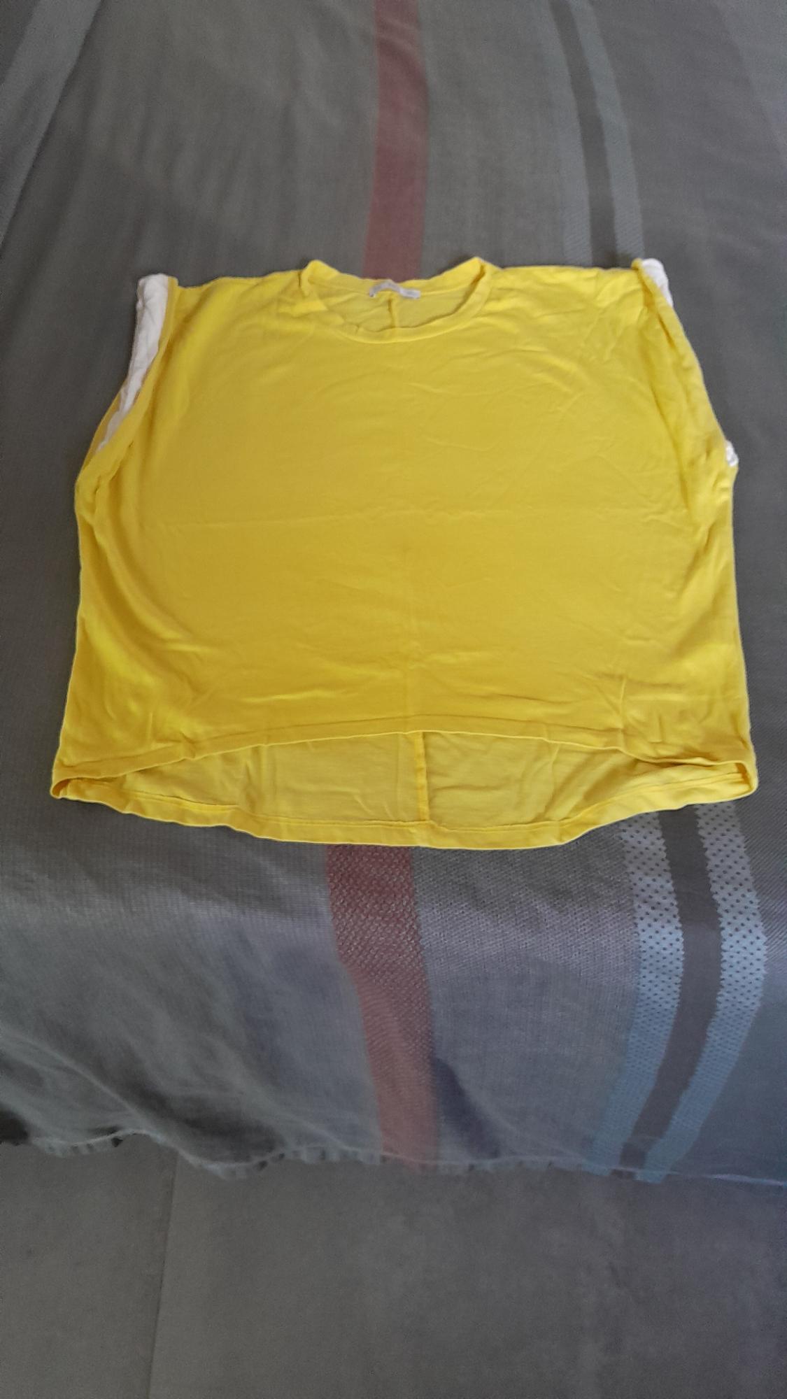 Yellow short-sleeved T-shirt laid out on a bed with a grey and brown striped bedspread.