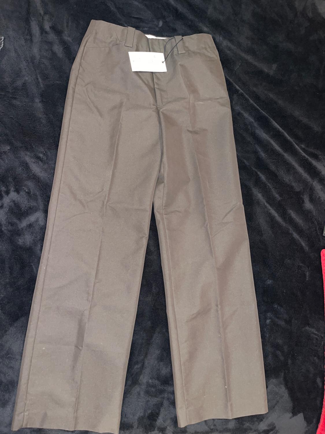 Brown dress trousers on a black surface, with a white tag hanging from the waistband.