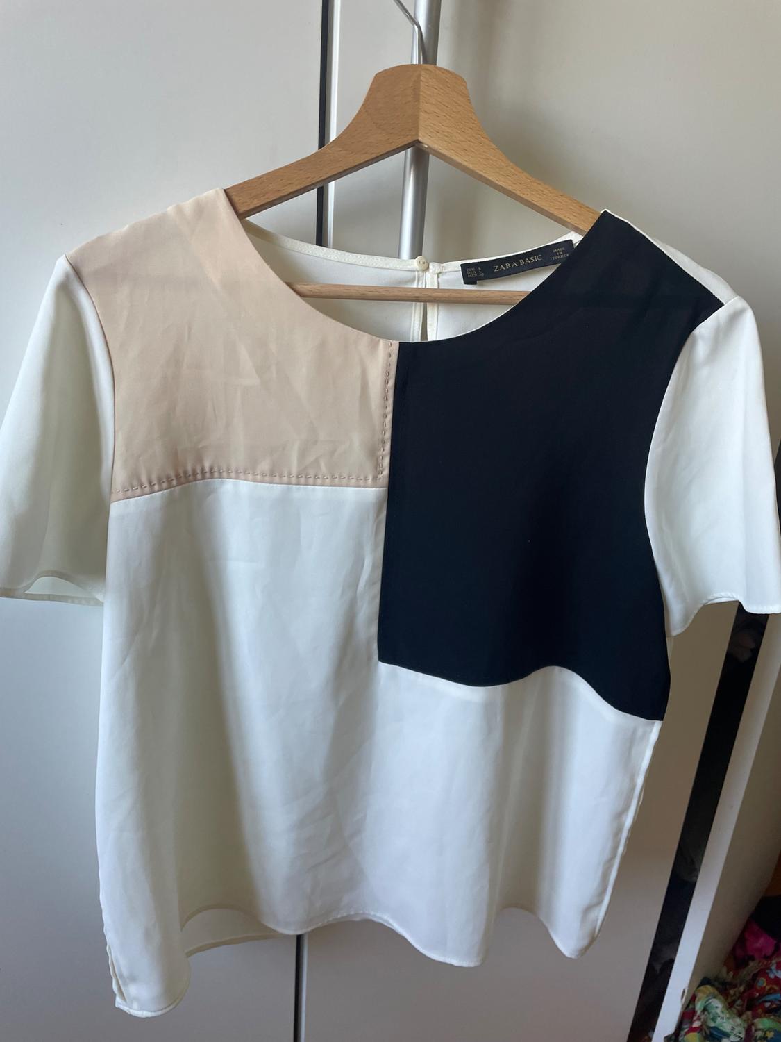 Front view of a blouse with white, black and beige colour blocking, a round neck and short sleeves.