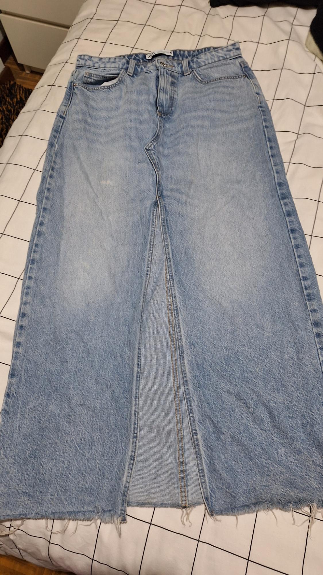 Light blue denim maxi skirt with a front slit, placed on a bed with a black and white checked quilt.