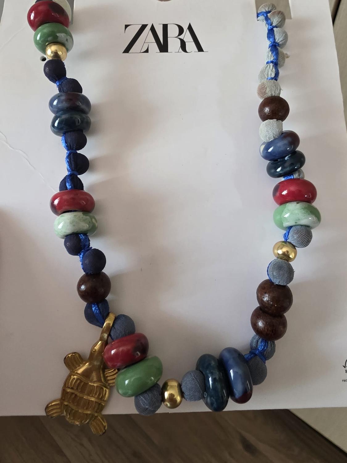 Multicoloured beaded necklace with a gold-tone turtle pendant on white card featuring the ZARA logo.