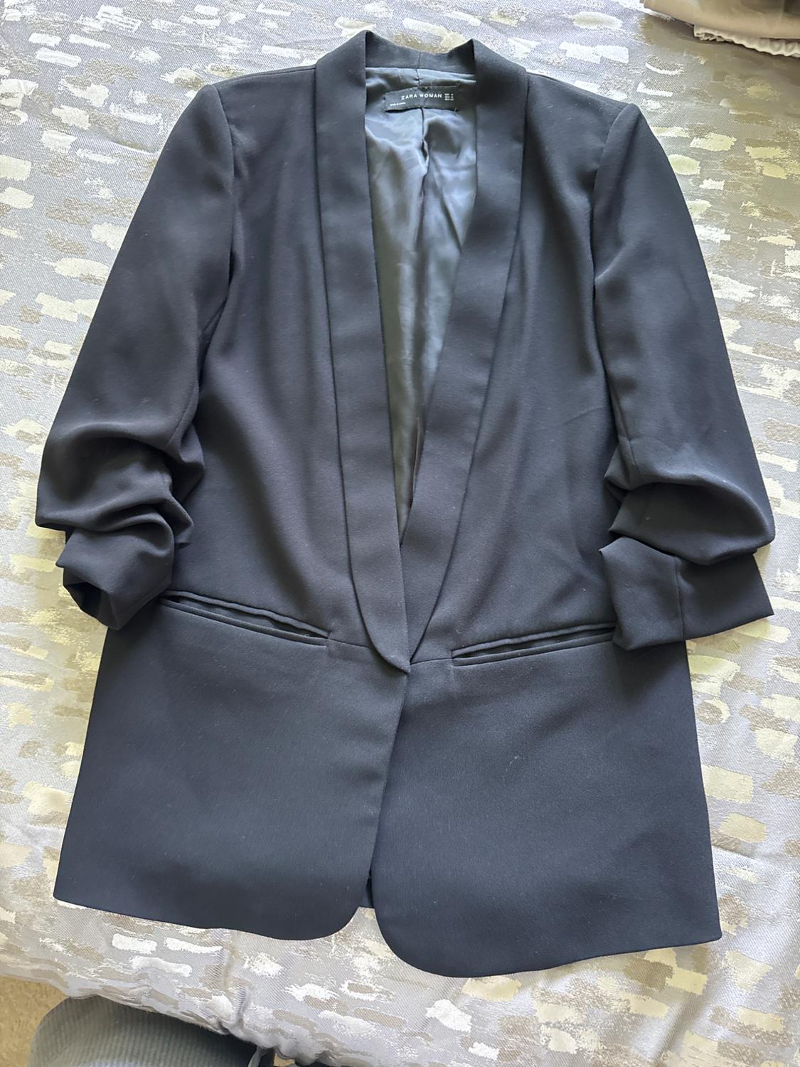 Front view of a black blazer with wide lapels and side pockets.